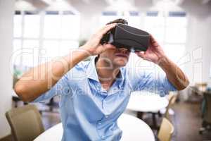 Executive holding virtual reality headset sitting at office