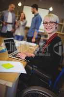 Smiling disabled businesswoman using laptop at desk
