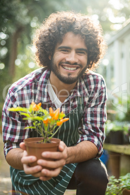 Gardener holding potted plant while kneeling