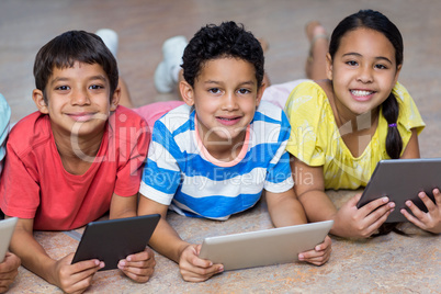 Children using digital tablets while lying on floor