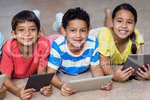 Children using digital tablets while lying on floor