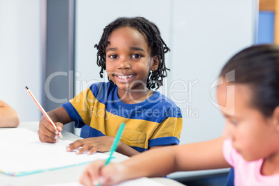 Schoolboy with classmate writing on book