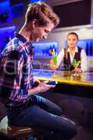 Man using mobile phone with bartender standing