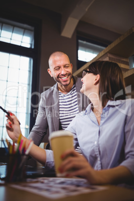 Coworkers smiling while discussing at desk
