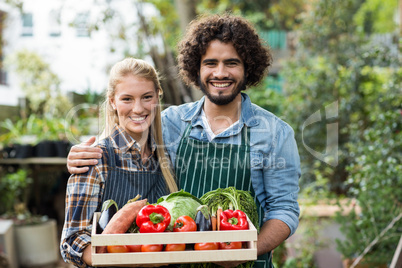 Happy couple holding vegetables crate