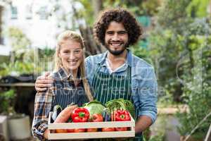 Happy couple holding vegetables crate