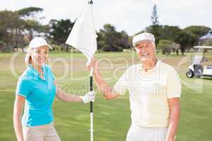 Smiling golfer couple holding white flag