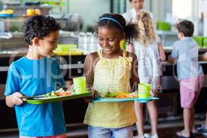 Schoolchildren holding food tray in canteen
