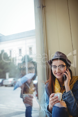 Portrait of happy woman listening to mobile phone at cafe