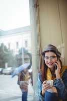 Portrait of happy woman listening to mobile phone at cafe