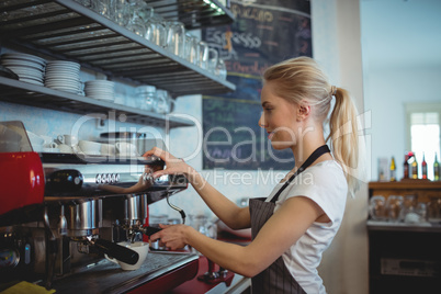 Side view of barista using espresso maker at coffee house