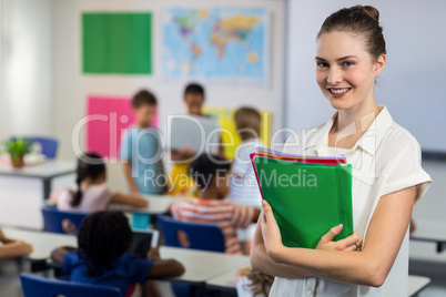 Female teacher with files standing in classroom