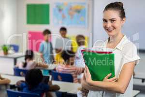 Female teacher with files standing in classroom