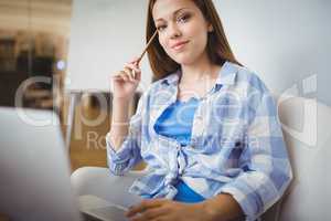 Portrait of businesswoman working on laptop in creative office