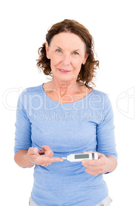 Portrait of smiling mature woman using blood glucose monitor