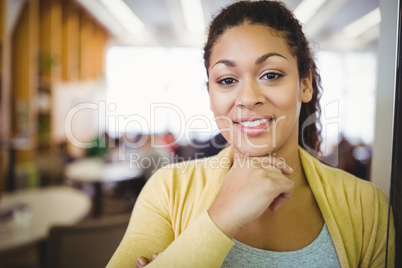 Portrait of smiling businesswoman with hand on chin in cafeteria