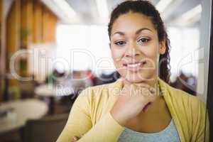 Portrait of smiling businesswoman with hand on chin in cafeteria