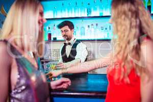 Bartender serving drinks to female customers