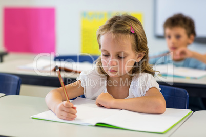 Serious girl writing on book