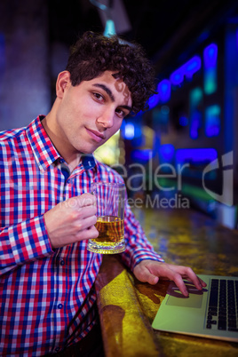 Portrait of man holding beer glass at bar counter