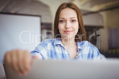 Young businesswoman holding laptop at desk in creative office