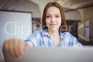 Young businesswoman holding laptop at desk in creative office