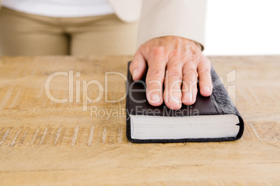 Midsection of woman with hand on bible