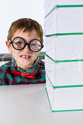 Portrait of boy by stacked books in classroom