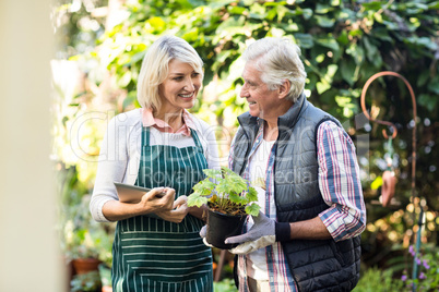 Gardeners standing with potted plant and clipboard