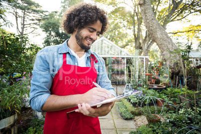 Male gardener writing in clipboard