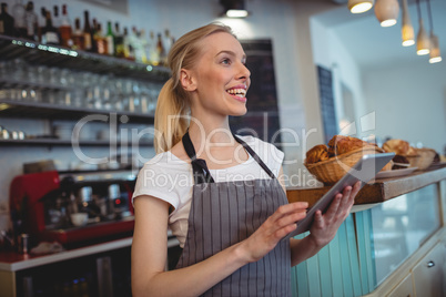 Happy barista with digital tablet at cafe