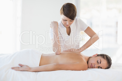 Masseuse giving massage to relaxed woman