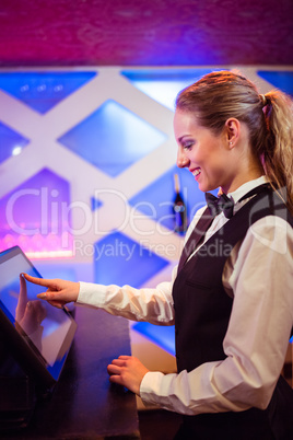 Barmaid smiling while using modern cash register