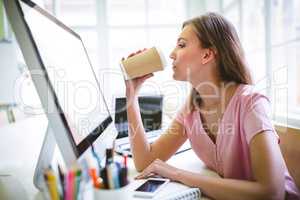 Graphic designer drinking coffee at desk