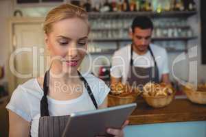 Waitress using tablet computer with colleague in background