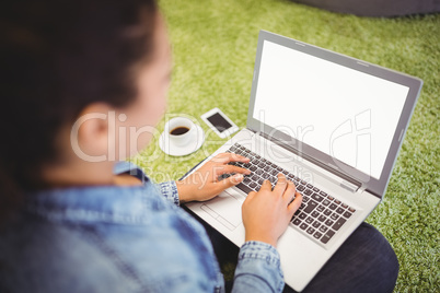 Businesswoman using laptop while sitting on carpet
