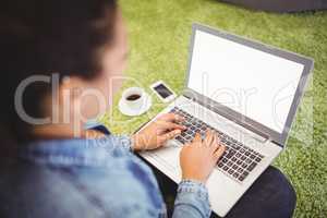 Businesswoman using laptop while sitting on carpet
