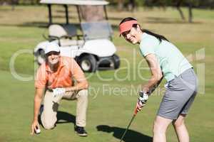 Portrait of smiling woman playing golf while standing by man