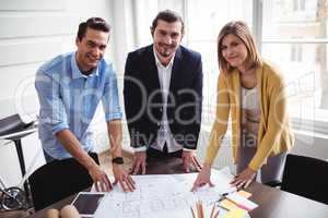 Smiling business people with blueprint