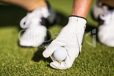 Cropped image of man placing golf ball on tee