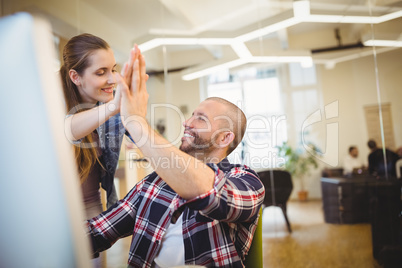 Businessman giving high-five to female colleague in office