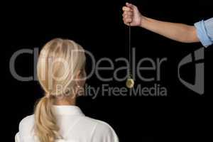 Cropped image of hypnotherapist holding pendulum by woman