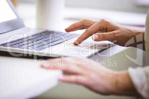 Cropped image of businesswoman using laptop at office