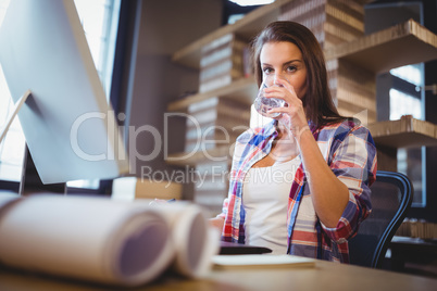 Businesswoman drinking water in creative office