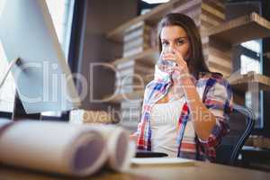 Businesswoman drinking water in creative office