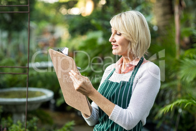 Female gardener writing in clipboard