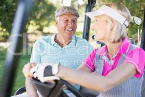 Confident couple sitting in golf buggy