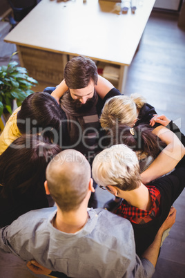 Creative business people forming huddle in office