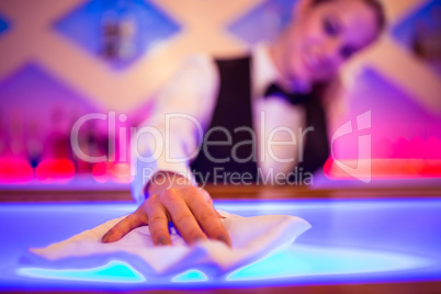 Barmaid cleaning counter with napkin
