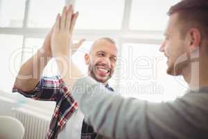 Male coworkers giving high-five